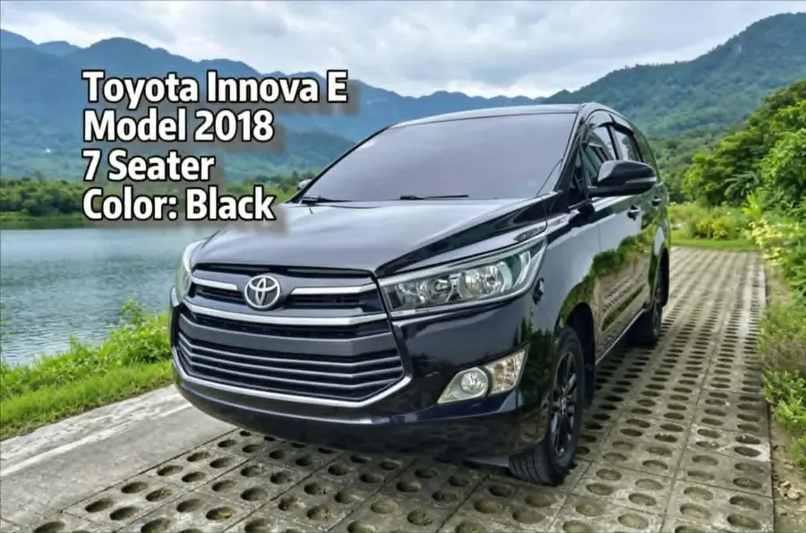 Black 2018 Toyota Innova E seven-seater parked beside a lake with mountains behind