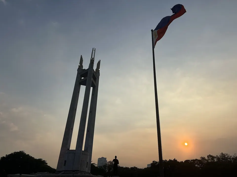 The three pylons of the Quezon Memorial Shrine against a sunset sky
