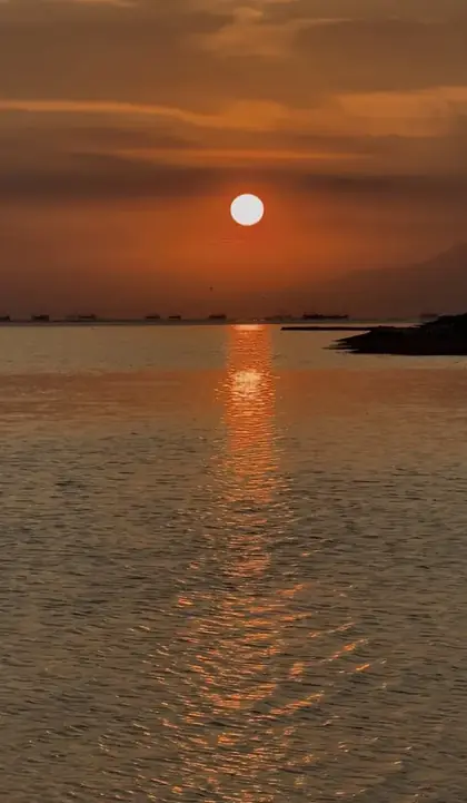 Sun setting over Manila Bay with fishing boats on the horizon